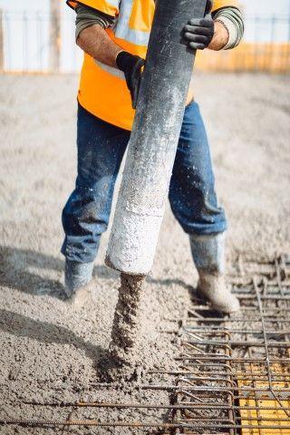 A concrete contractor in Dania Beach FL uses a hose to pour fresh cement over rebar on a job site.