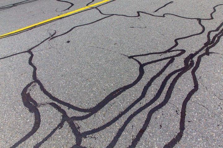 Asphalt pavement showing extensive branching cracks fixed by a concrete contractor in Dania Beach FL using crack sealant.