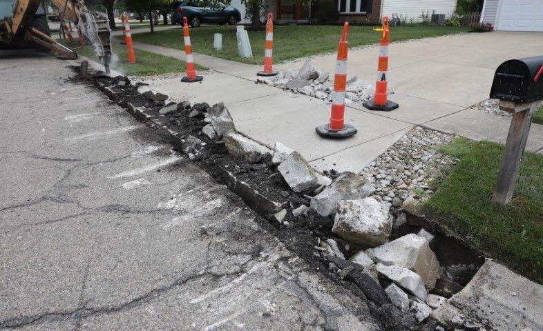 Orange safety cones mark a broken driveway edge where a concrete contractor in Dania Beach FL is breaking pavement.