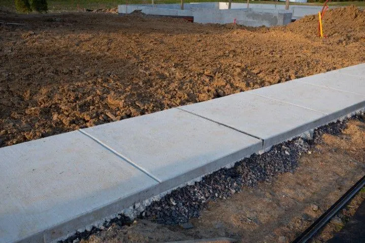 : Newly poured concrete walkway sections installed by a concrete contractor in Dania Beach FL next to a dirt lot.