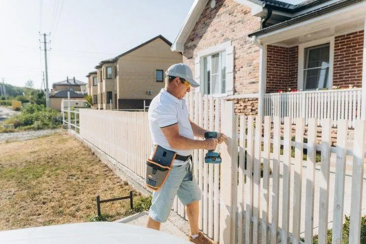 A contractor installing a white wooden picket fence for Paso Robles Fencing Pros, in Paso de Robles CA.