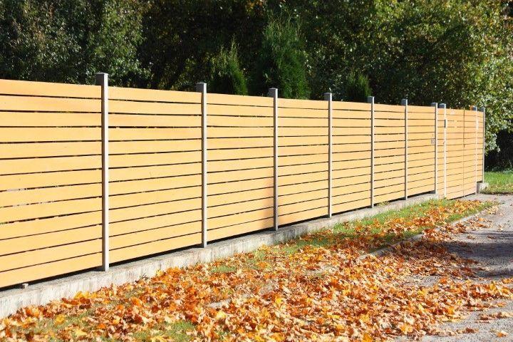 A modern wooden slat fence line with autumn leaves, built by Paso Robles Fencing Pros, in Paso de Robles CA.