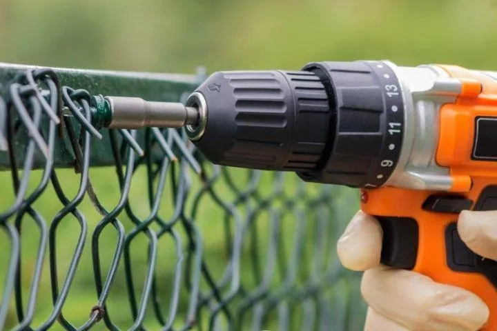 Close-up of a power drill fixing a chain-link fence, handled by an expert Fencing Contractor in Galt CA.