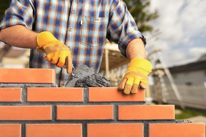 Clarington Masonry Craftsmen in Clarington ON laying red bricks and mortar with a trowel.
