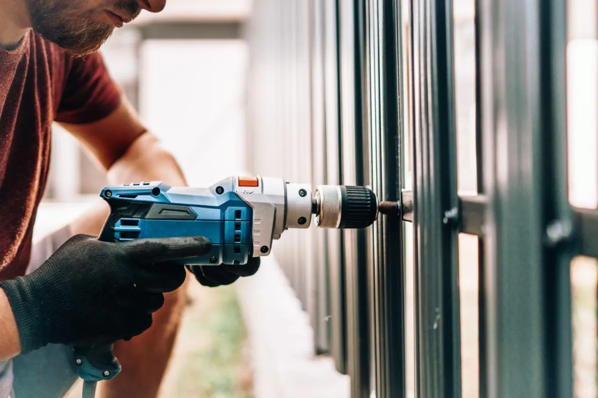 Sandusky Fencing Creations in Sandusky OH using a power drill on a metal fence structure.
