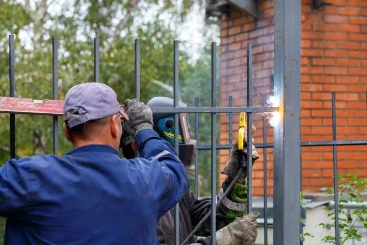 Sandusky Fencing Creations in Sandusky OH welding a metal fence panel outdoors.
