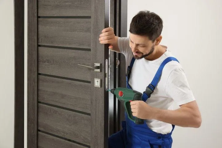 Wethersfield Carpentry Masters in Wethersfield CT technician using a power drill to install a dark wood door.