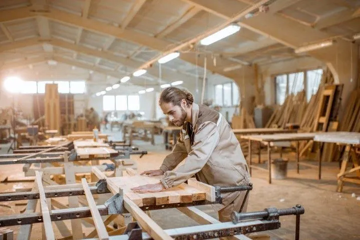 Wethersfield Carpentry Masters in Wethersfield CT craftsman assembling wooden pieces with clamps in a large workshop.