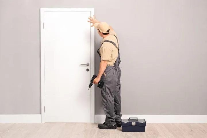 Wethersfield Carpentry Masters in Wethersfield CT technician in overalls examining a newly installed white door.