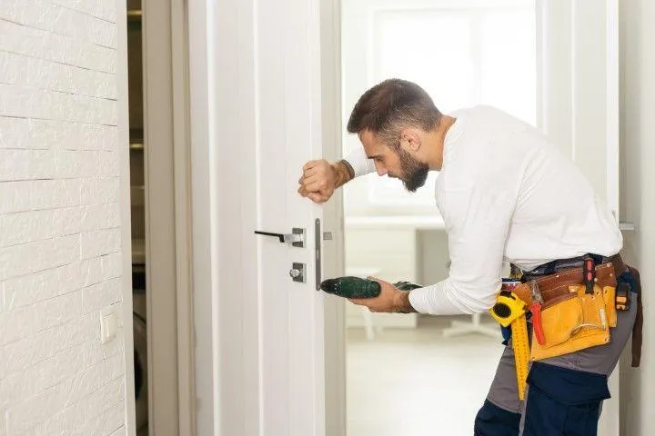 Wethersfield Carpentry Masters in Wethersfield CT carpenter installing a lock on a white interior door.
