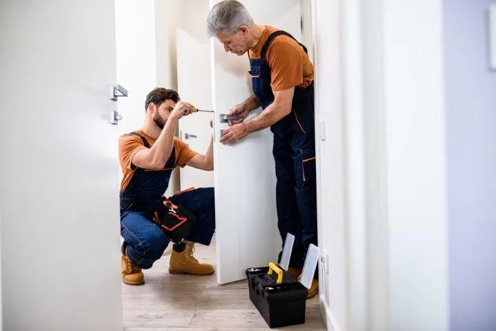 New Milford Carpentry Crafts in New Milford CT two carpenters installing hardware on a white interior door.