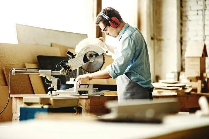 New Milford Carpentry Crafts in New Milford CT craftsman cutting timber using a power miter saw in shop.