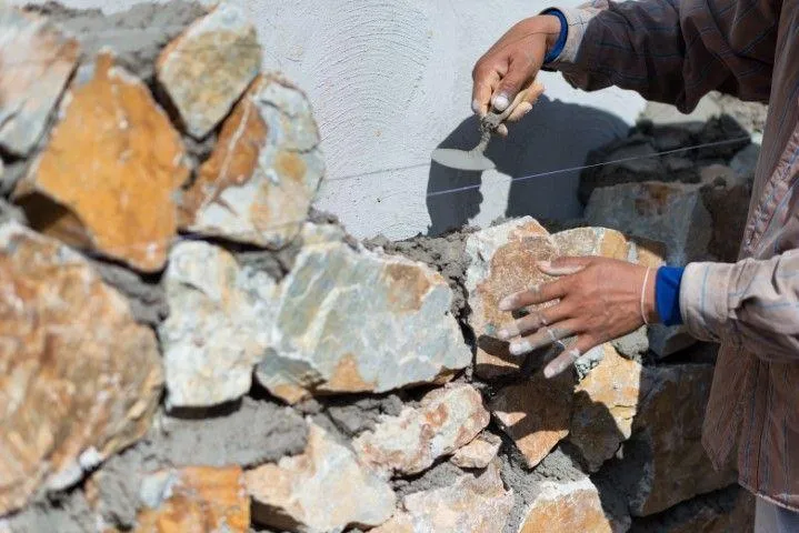 Clarington Masonry Craftsmen in Clarington ON placing natural stone blocks for a stone wall.