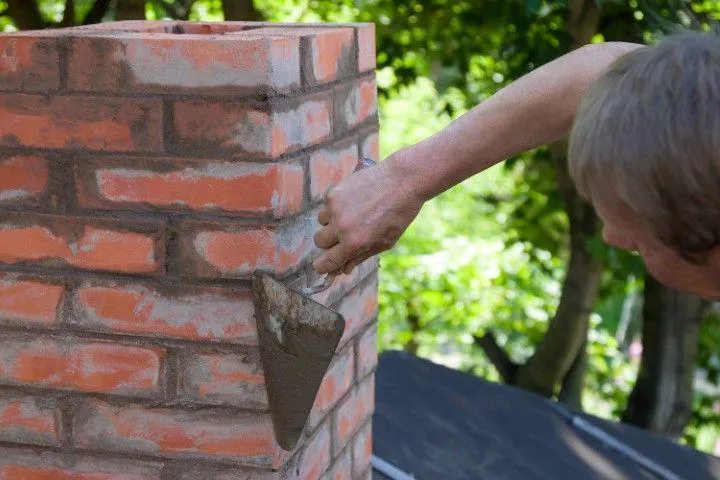 Clarington Masonry Craftsmen in Clarington ON applying mortar to a brick chimney structure.