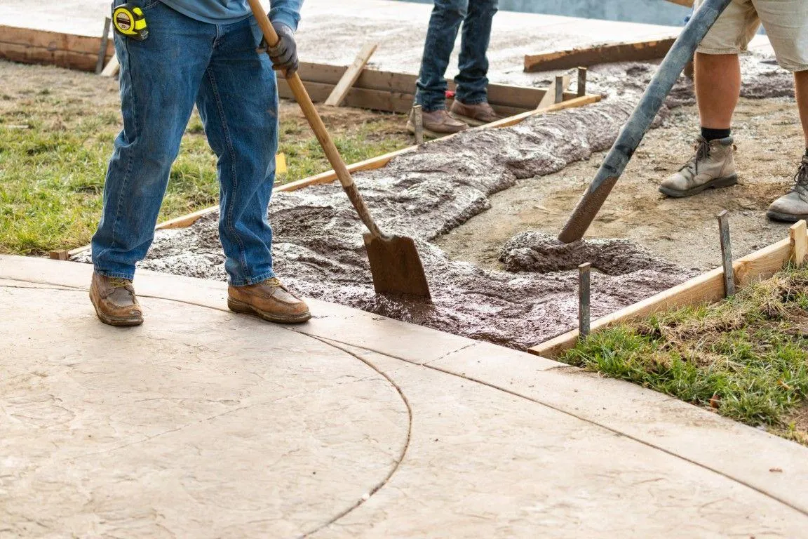 A concrete contractor in Dania Beach FL uses a hose to pour fresh cement over rebar on a job site.