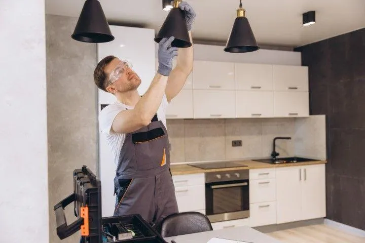 Grandview Electrical Pro in Grandview MO adjusting stylish modern black pendant lighting fixtures in a kitchen
