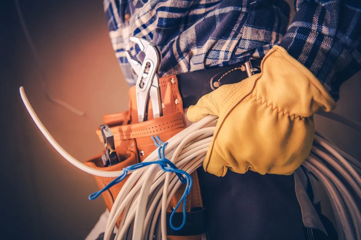 An electrician holding a bundle of white wires with a tool belt from Falls Electric Services Company in Falls PA.