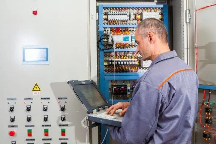 Grandview Electrical Pro in Grandview MO programming and testing industrial control panels using a laptop.