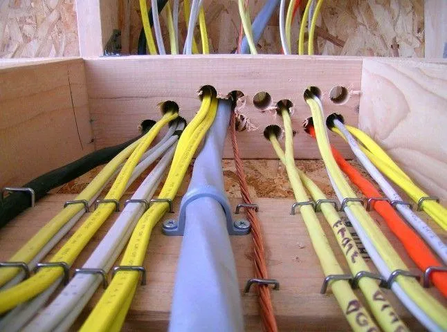 Grandview Electrical Pro in Grandview MO installing organized multi-colored electrical wiring through wooden framing.