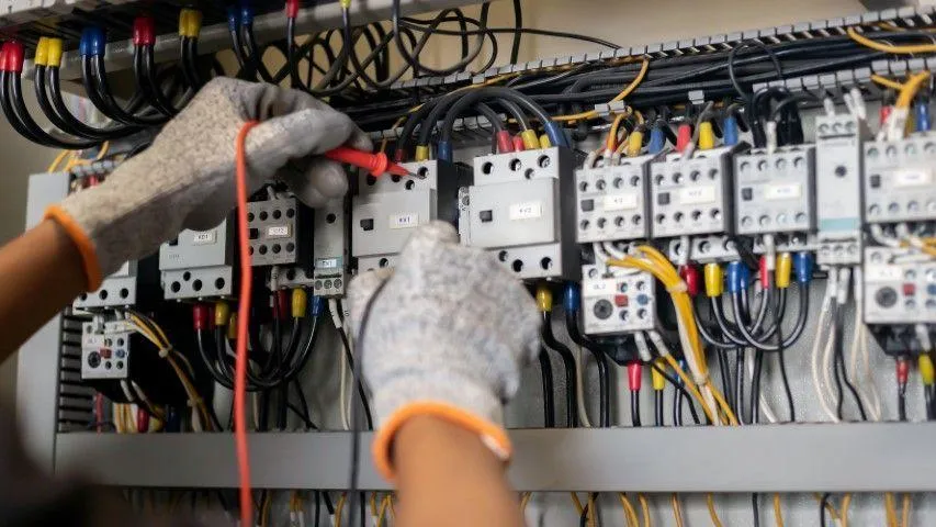Grandview Electrical Pro in Grandview MO testing components inside a dense industrial electrical control box.