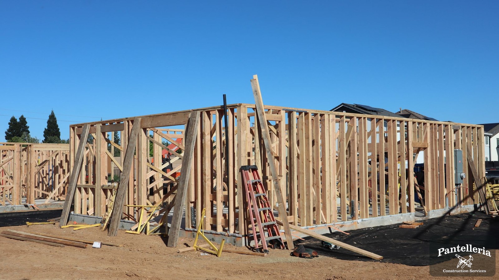 New custom home under construction with wall framing standing on a poured foundation