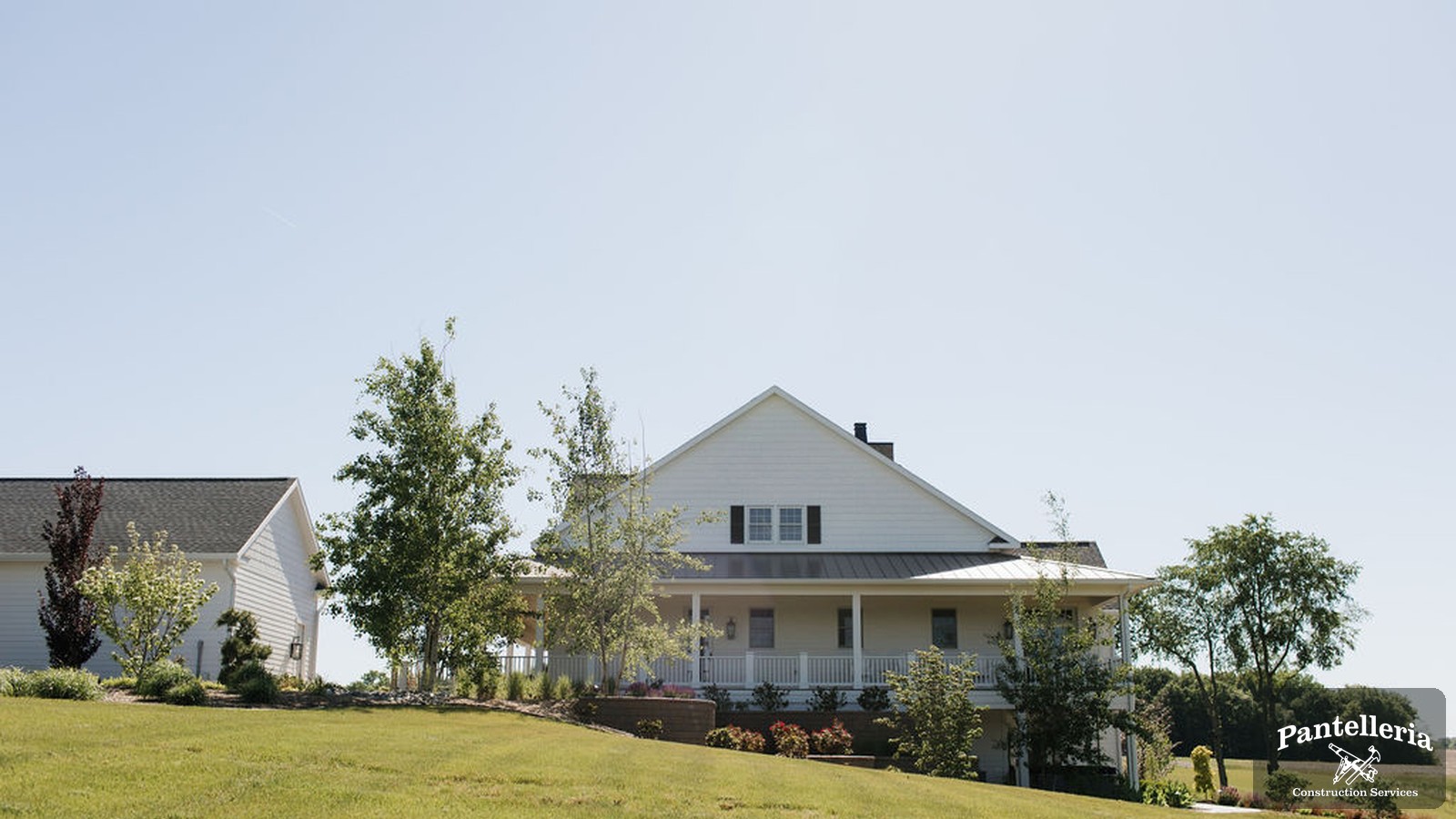 White farmhouse-style custom home built by Pantelleria Construction on an open Southwest Michigan lot with a wide grassy front yard