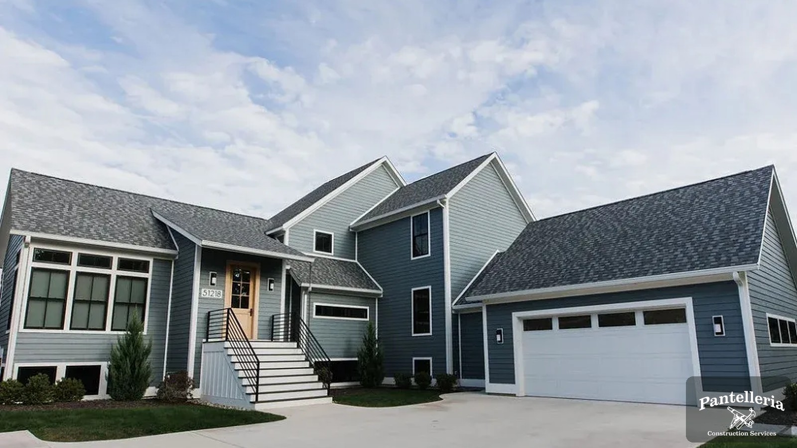 Completed blue-gray custom home with gabled rooflines and attached garage built by Pantelleria Construction