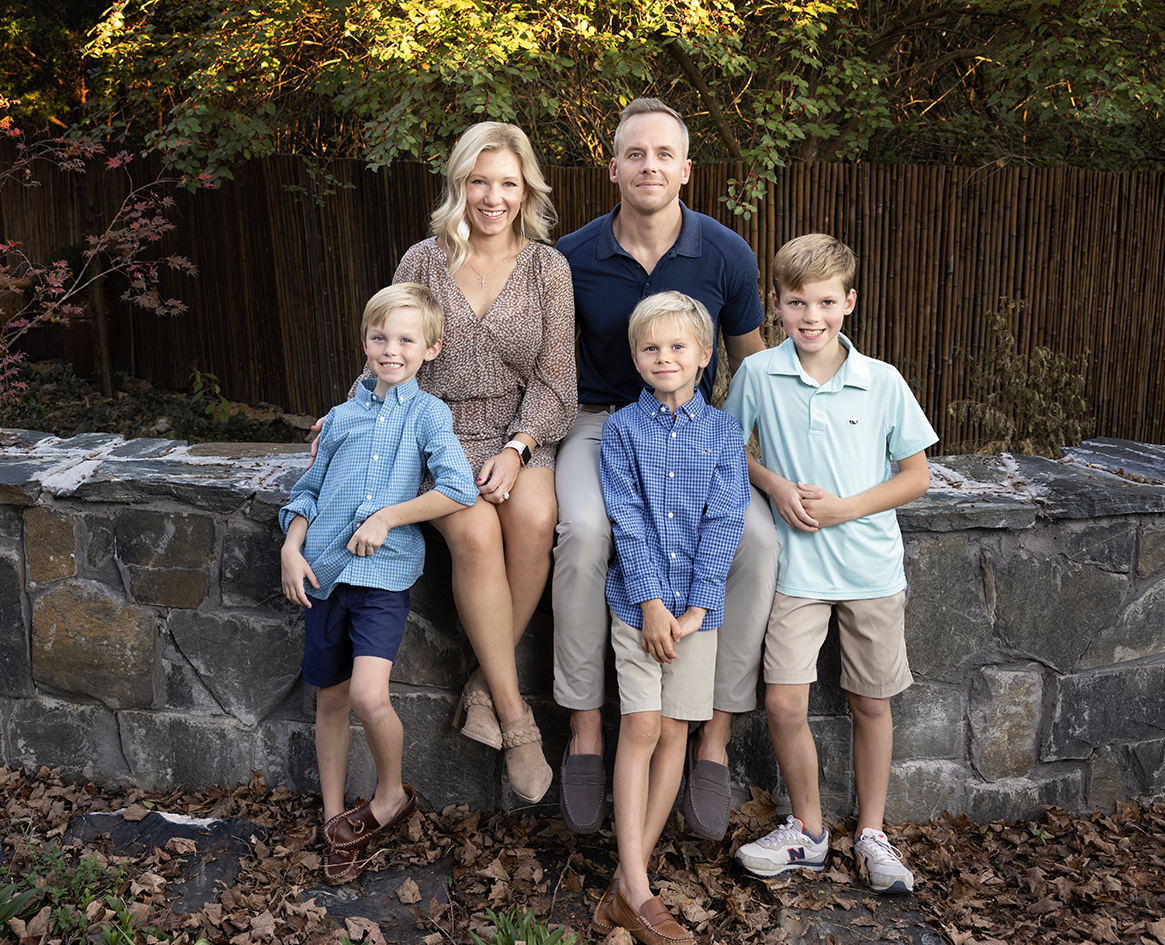 Family portrait outdoors beside a stone wall.