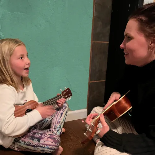 Mother and child bonding through playing ukulele together.
