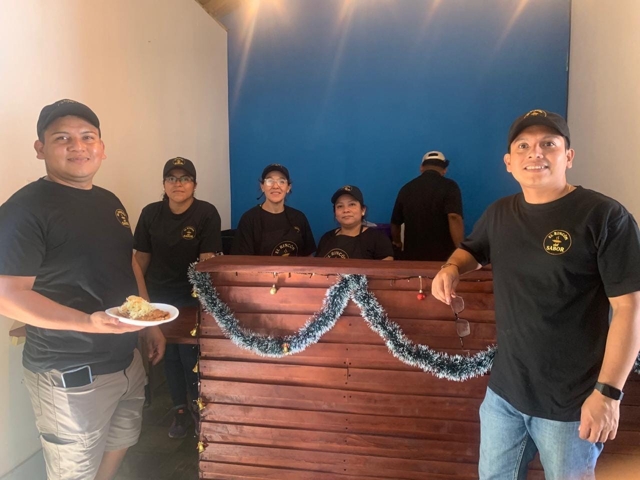 Toma cenital de una bandeja latinoamericana con empanadas coloridas y hierbas frescas sobre una mesa rústica; la luz natural realza las texturas y los colores.