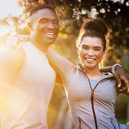 Happy, fit couple in athletic clothing embracing outdoors, reflecting wellness, support, and shared fitness goals.