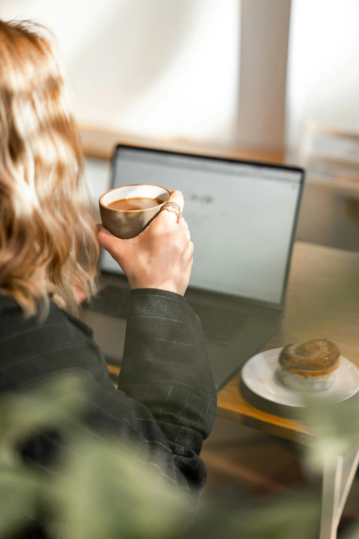 holding coffee working on laptop