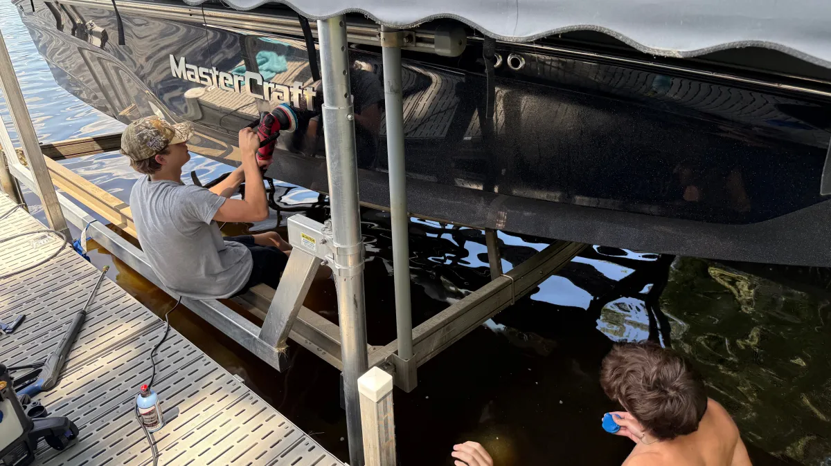 Smoove Auto Detailing polishing speedboat with machine buffer on dock over Lake Wissota Chippewa Falls WI during professional boat detailing service