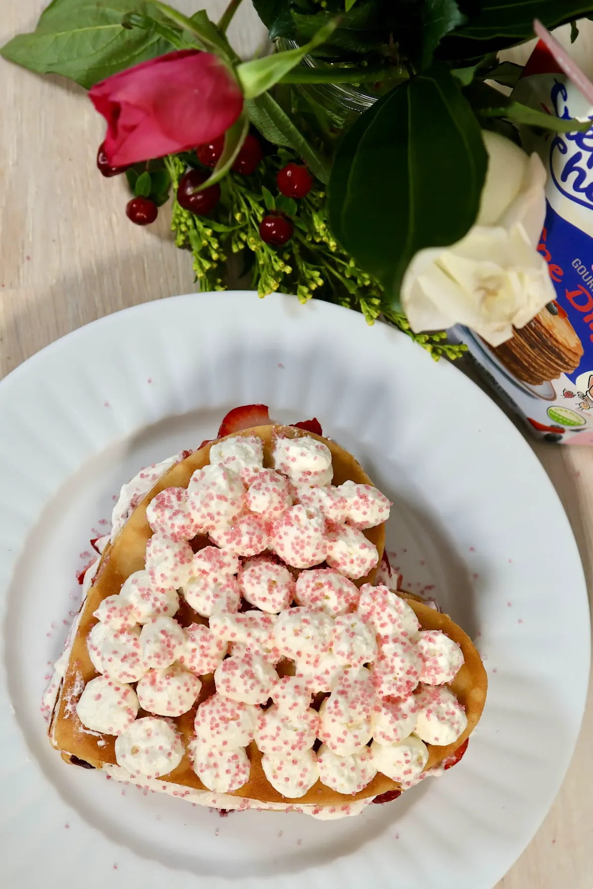Top view of a heart shaped sweet crêpe cake made with frozen sweet crêpe at home, layered with cream and fruit on a white ceramic plate