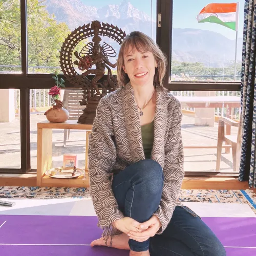 A woman sitting on a yoga mat with the Indian flag in the background.