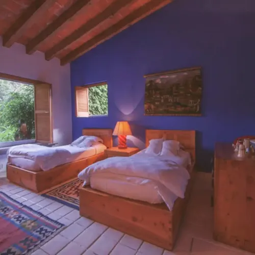 Cozy bedroom featuring blue walls and wooden beams, warm and inviting.
