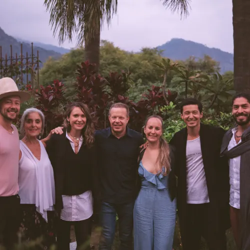 Smiling individuals posing for a photo with a scenic mountain backdrop.