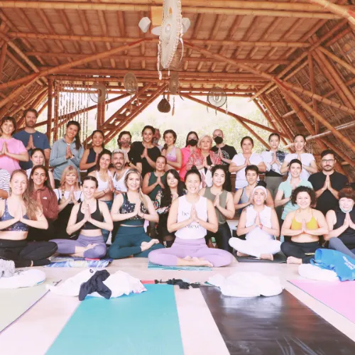 Group of people gathered on mats in a room, smiling for a picture.