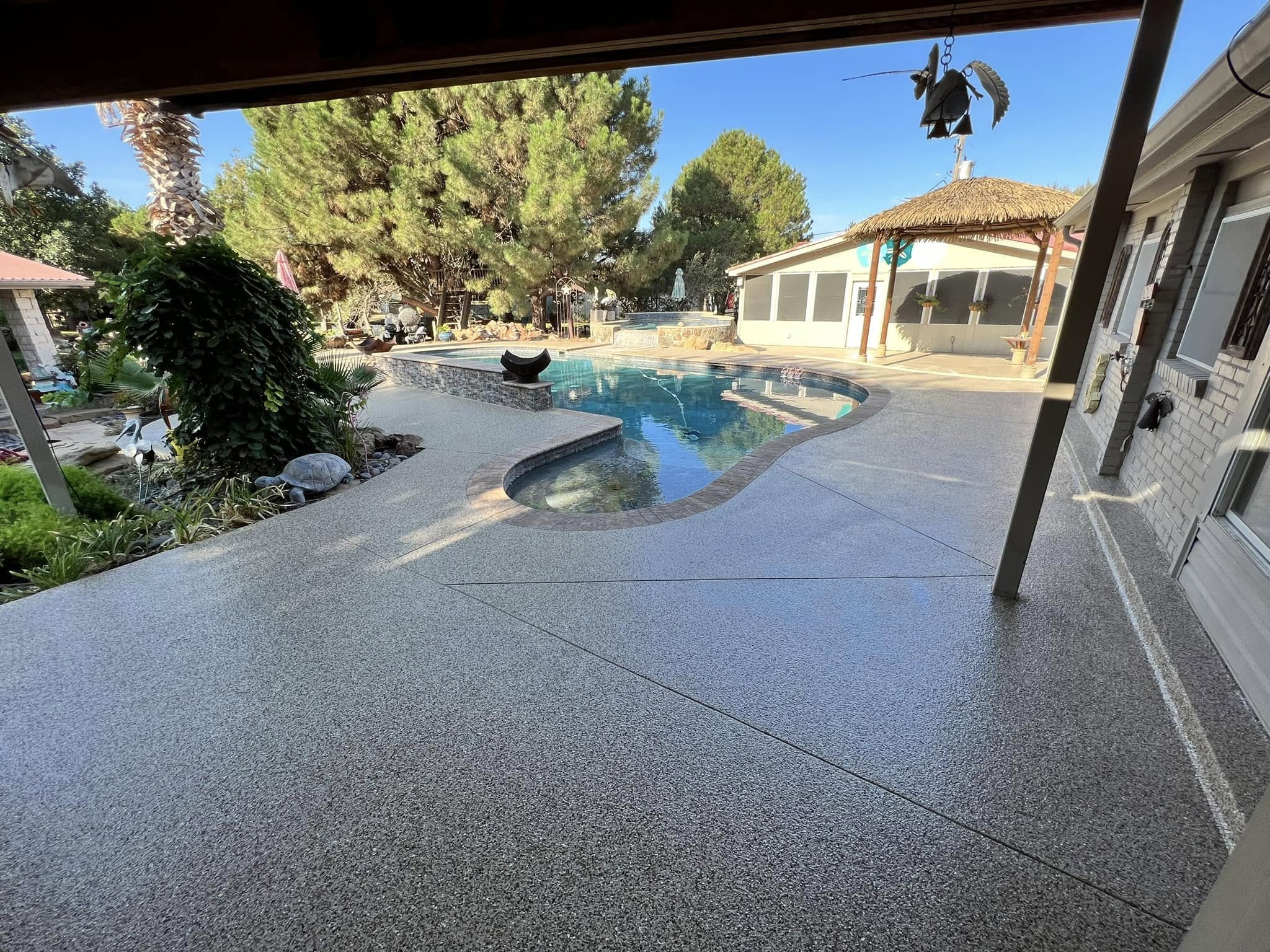 gray flake pool deck coating around a backyard pool in Odessa, TX