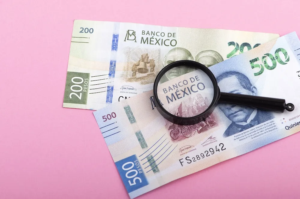Mexican peso banknotes with a magnifying glass, representing secure escrow funds and financial verification when buying property in Mexico. Dream Baja Realty
