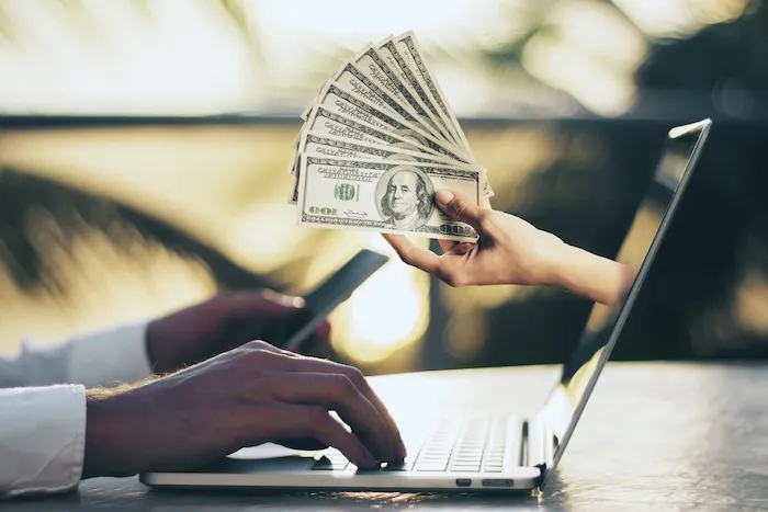 wire transfer during a mexican property transaction showing a hand with USD coming out of a computer screen. Dream Baja Realty