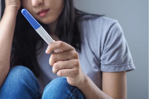 concerned woman holding pregnancy test