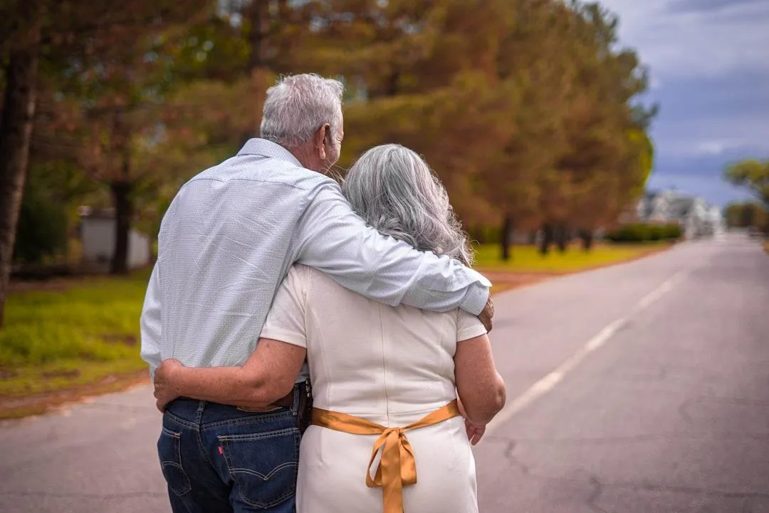Senior couple walking arm-in-arm down a quiet tree-lined road