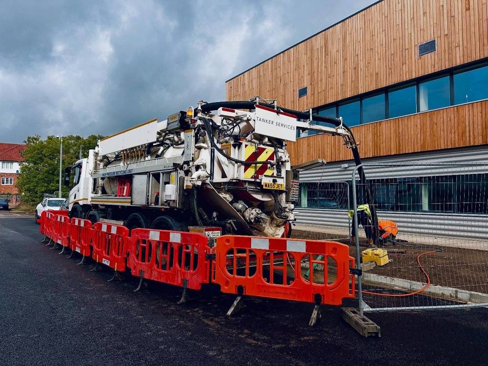 Vacuum tanker with jetting boom extended at a commercial drainage site