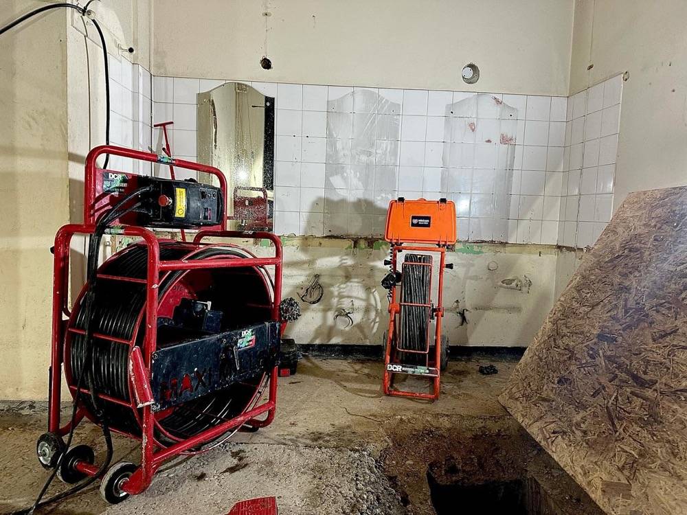 CCTV and jetting equipment set up in a commercial kitchen basement with open channel drain