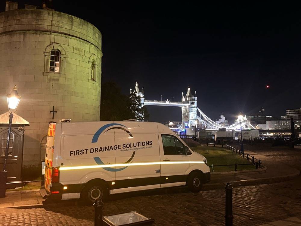 UK Drain Services van at the Tower of London with Tower Bridge illuminated at night