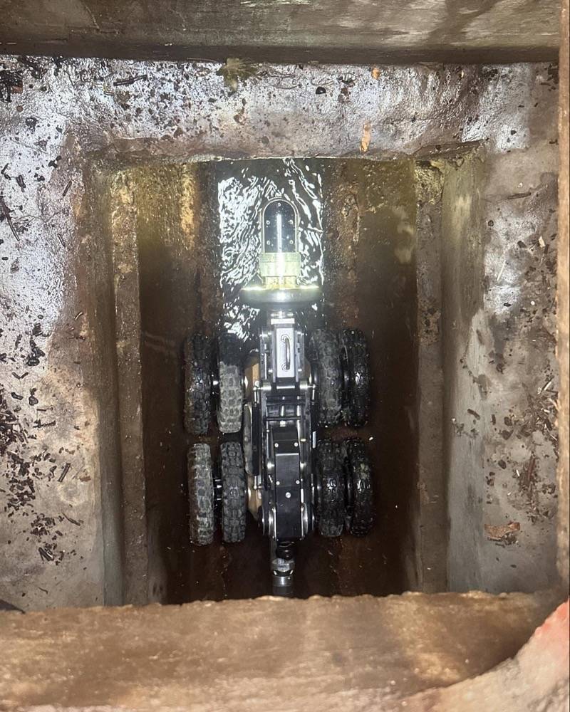 CCTV crawler robot inside a drain pipe with green inspection light