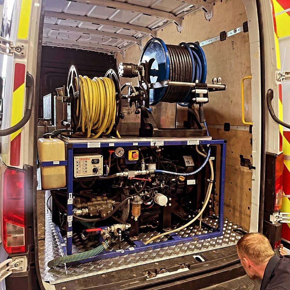 Interior of a UK Drain Services van showing high-pressure jetting equipment and hose reels
