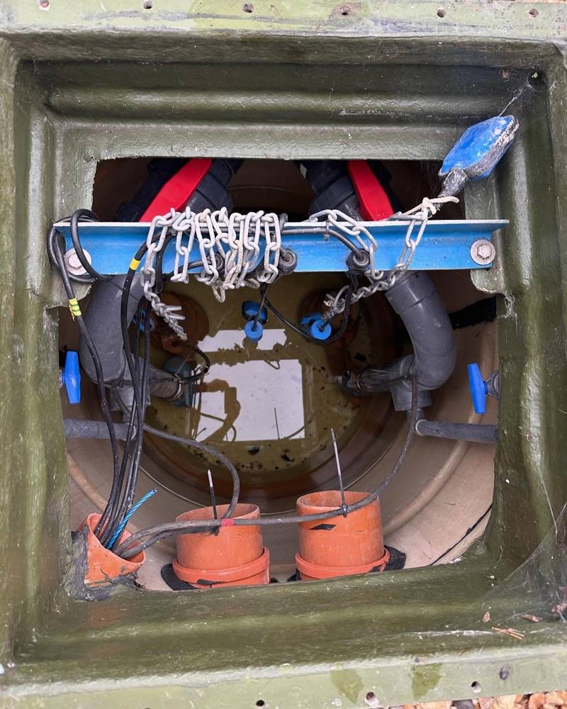 Survey equipment being lowered into a manhole chamber for inspection