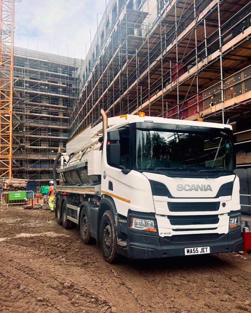 Scania vacuum tanker at a major construction site with crane and scaffolding